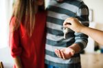 брокер подава ключове на млада двойка след покупка на апартамент