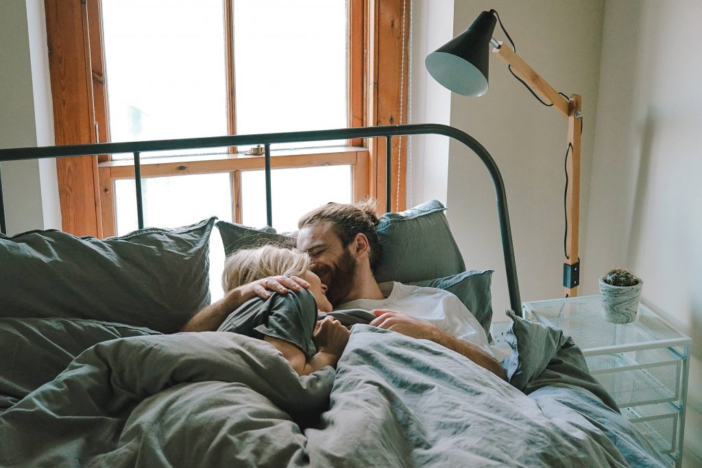 мъж и жена се гушкат в леглото
