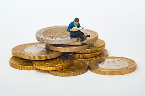 фигура на мъж седи върху купчина от монети